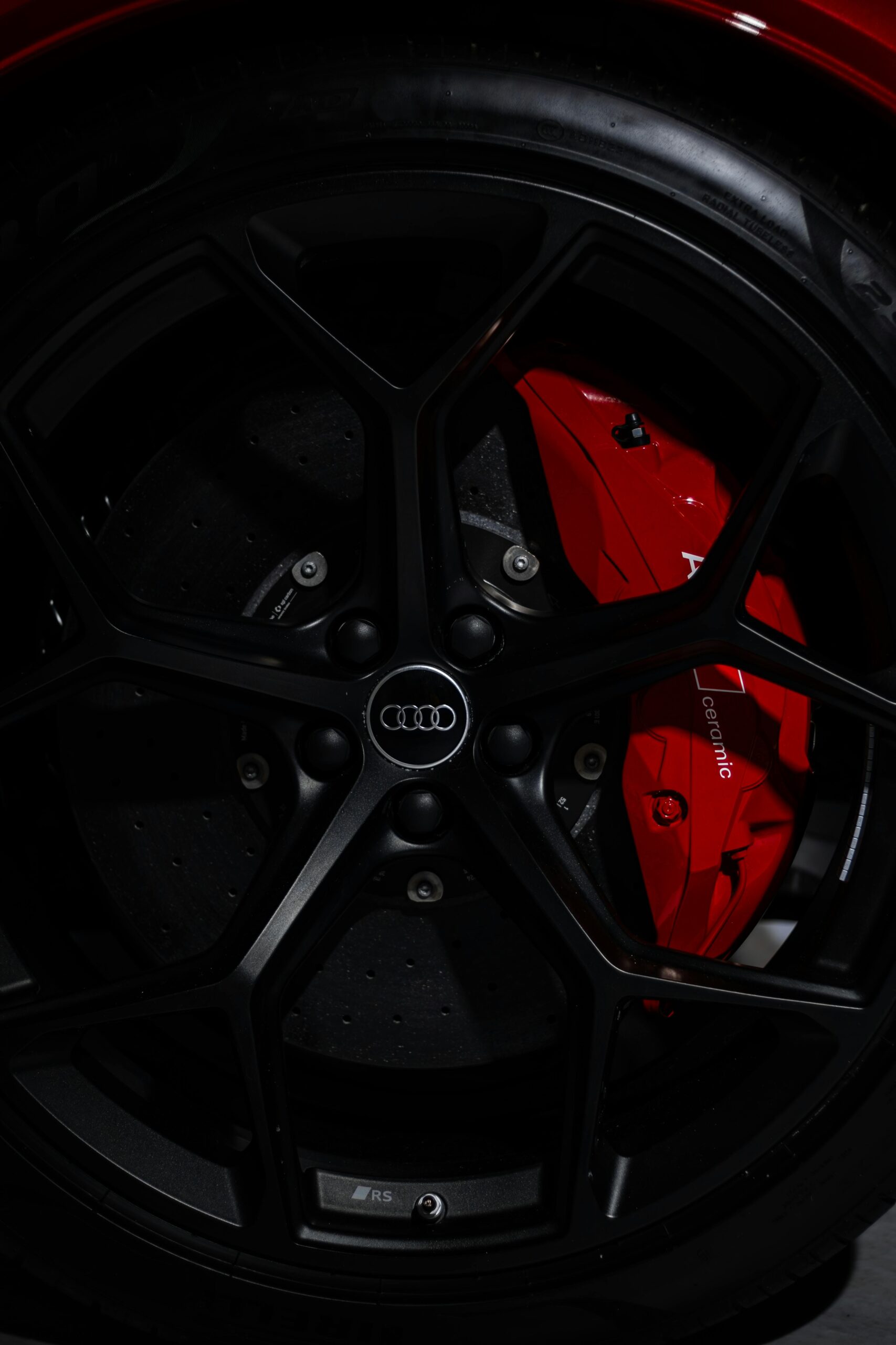 Detailed shot of an Audi RS wheel, showcasing the red brake caliper and logo.